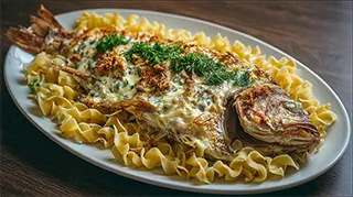 photo of baked carp with sour cream sauce and egg noodles on a white platter