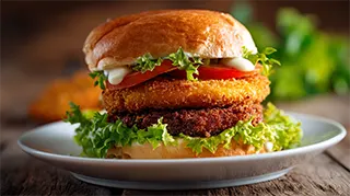 Photo of carp sausage patties on a hamburger bun with lettuce, tomato and mayonnaise