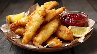 photo of deep fried carp strips on paper towel with red sauce on the side