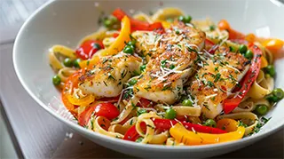 Photo of a hearty bowl of catfish pasta primavera with bell peppers and fettuccine noodles