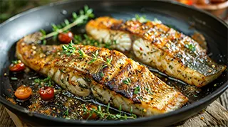 Photo of pan grilled catfish fillets with golden crispy coating and garnished with fresh herbs